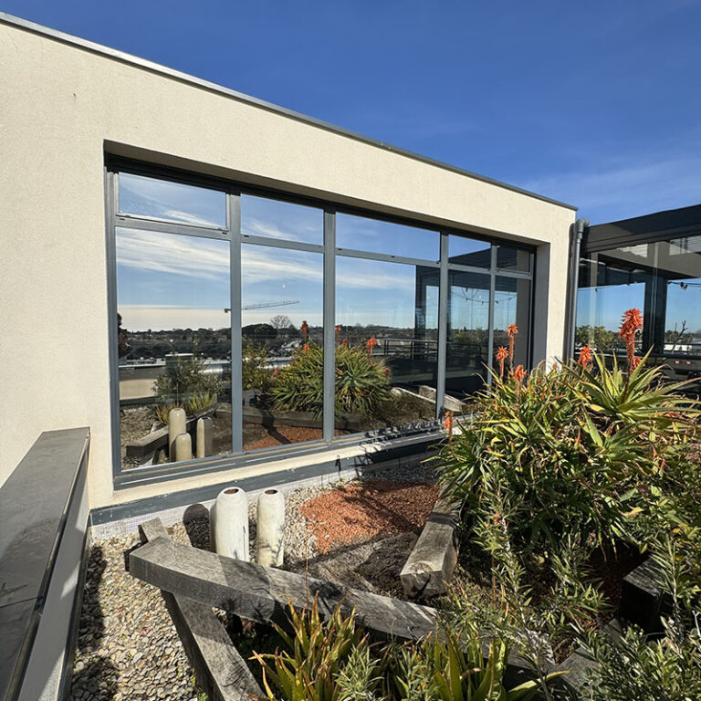 façade d'une maison dont la baie vitrée est équipée d'un film thermique UV effet miroir